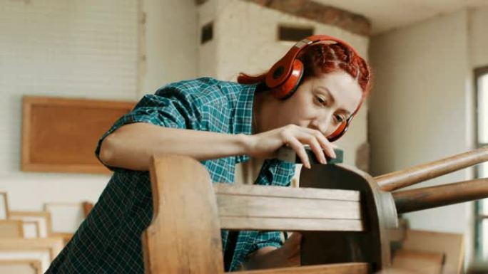 女人听音乐和打磨木椅