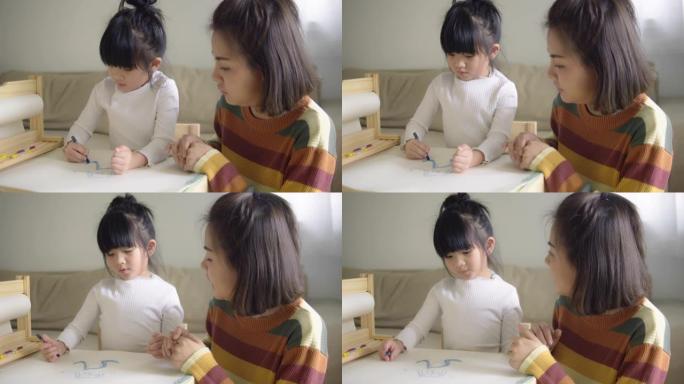 快乐的亚洲男孩和他的母亲在家里的客厅用蜡笔画画。