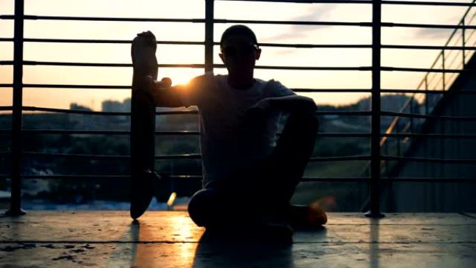 滑板手坐在日落背景上，特写镜头。