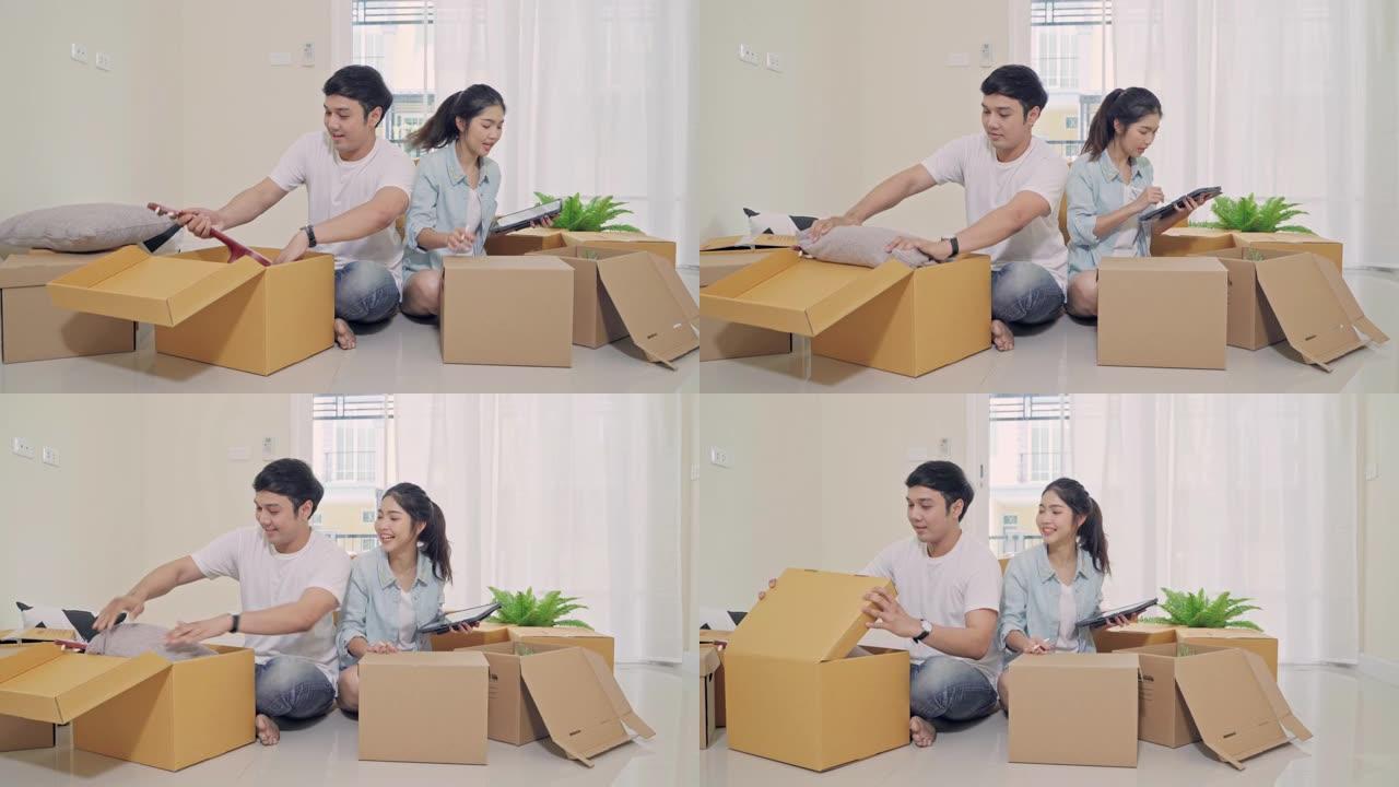 4k分辨率年轻的亚洲夫妇在搬家日检查和包装箱进入新家。搬迁概念
