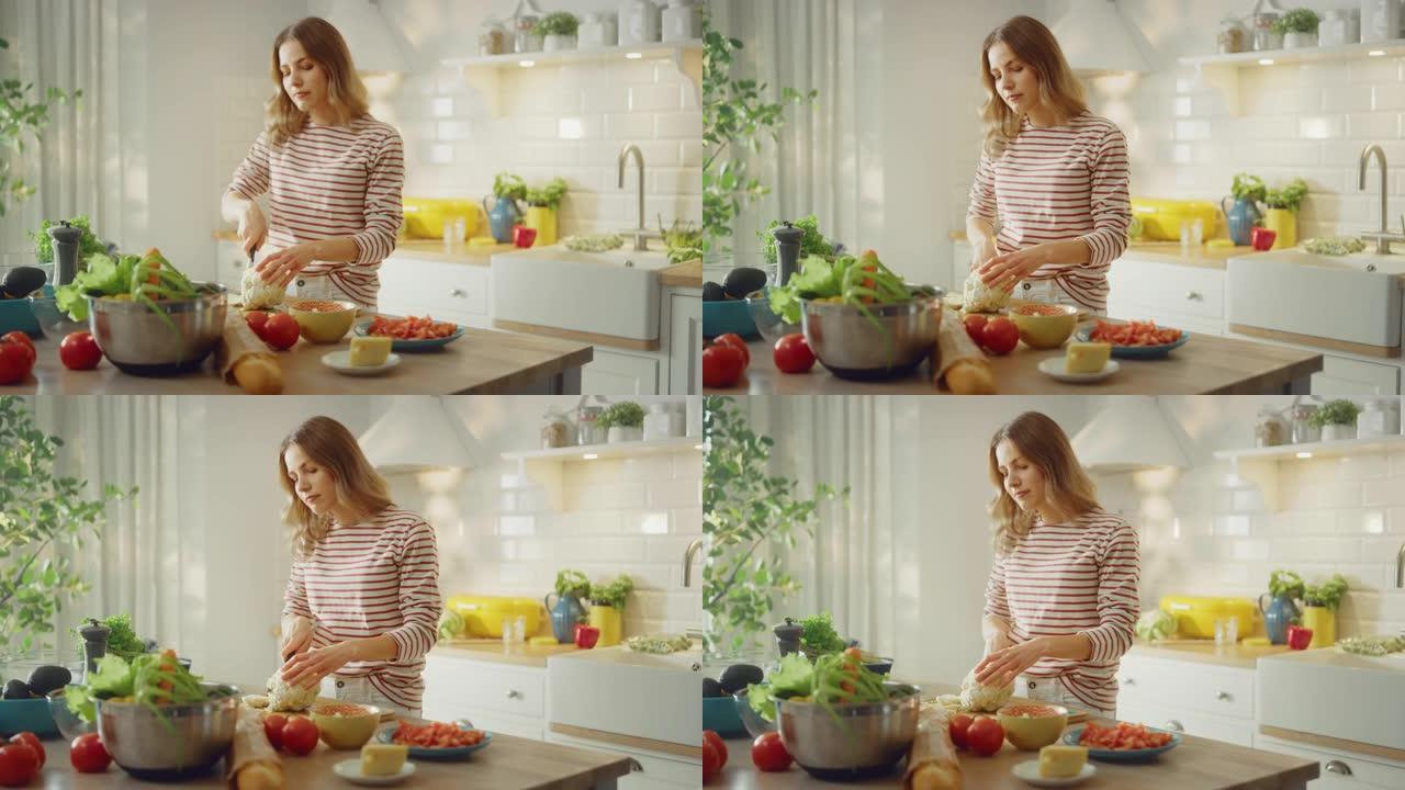 穿着条纹套头衫的年轻女性正在现代阳光明媚的厨房里制作健康的有机沙拉。正宗的女人正在用刀切碎花椰菜。天