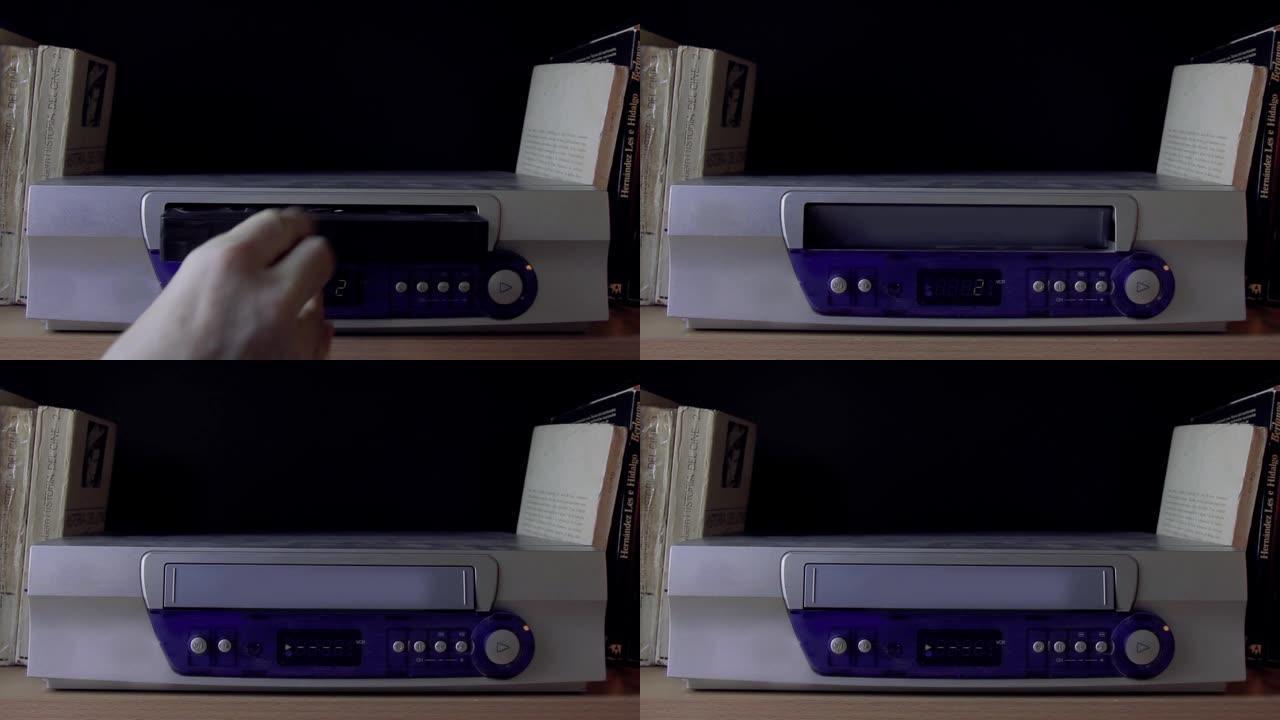 男性手在盒式磁带播放器中插入VHS。特写。