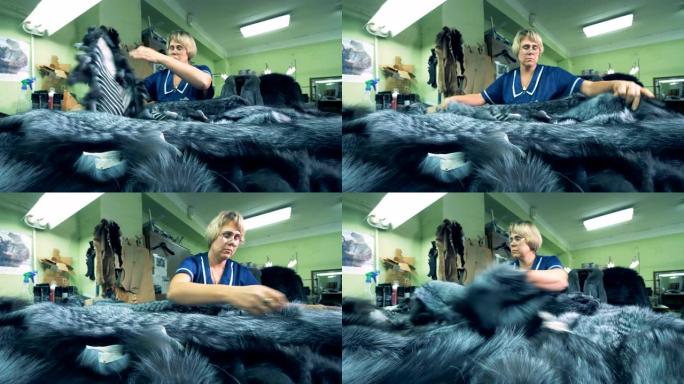 一个女人在工厂里用很多动物皮毛工作，特写镜头。