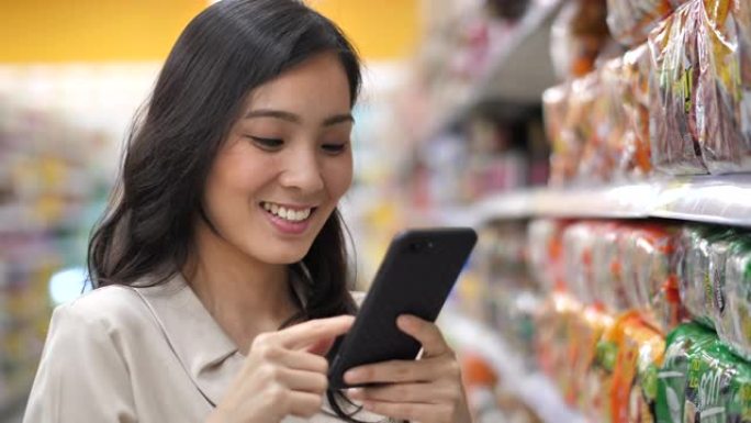 在超市使用智能手机的亚洲女性