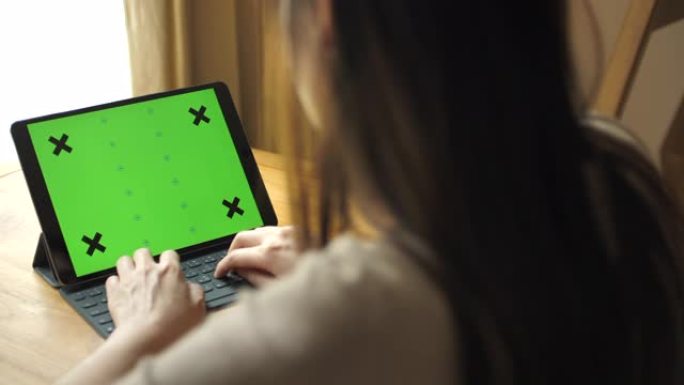 亚洲女性使用数字平板电脑绿屏和家庭。