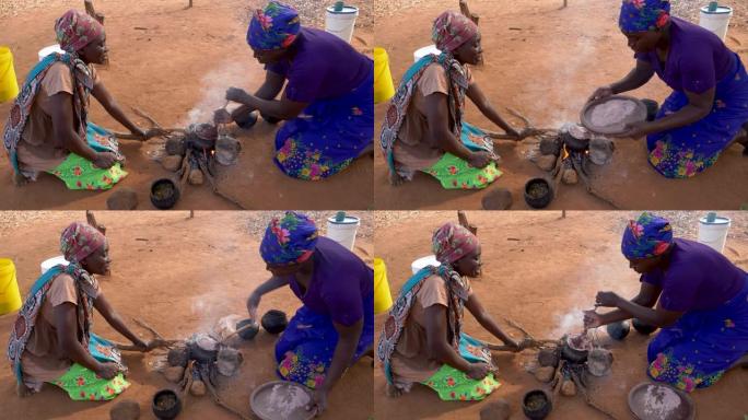 津巴布韦，两名妇女在传统的陶罐中煮高粱