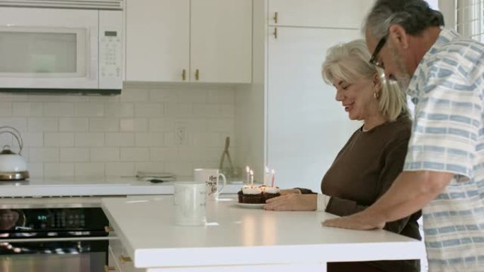 高级男子将纸杯蛋糕放在盘子里给妻子庆祝生日