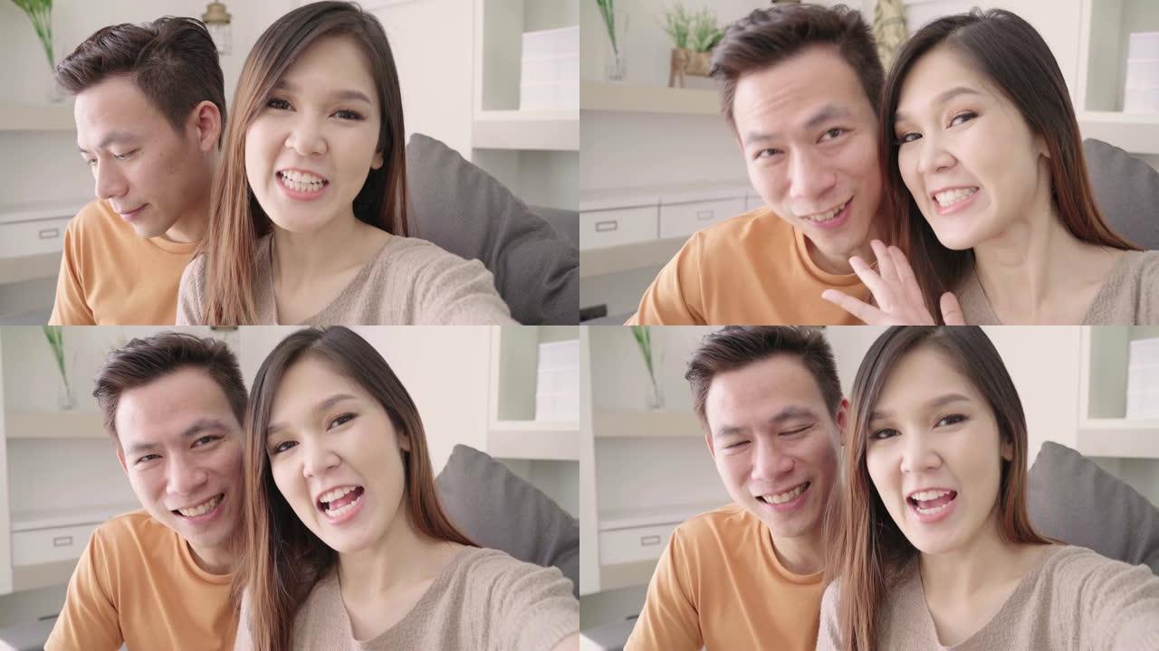 亚洲夫妇在家里的客厅与朋友使用智能手机视频通话，甜蜜的夫妇在家放松时躺在沙发上享受爱情时刻。生活方式