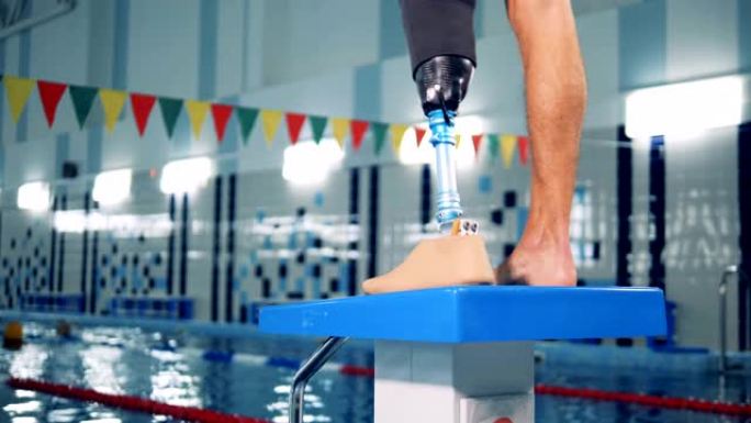 在游泳池中关闭一条男性健康腿和一条假肢