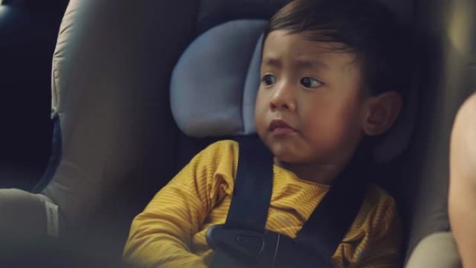 亚洲男婴在他的儿童安全汽车座椅-