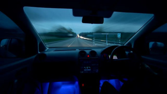 该男子在傍晚的城市驾驶带有虚拟导航仪的汽车。过度下垂