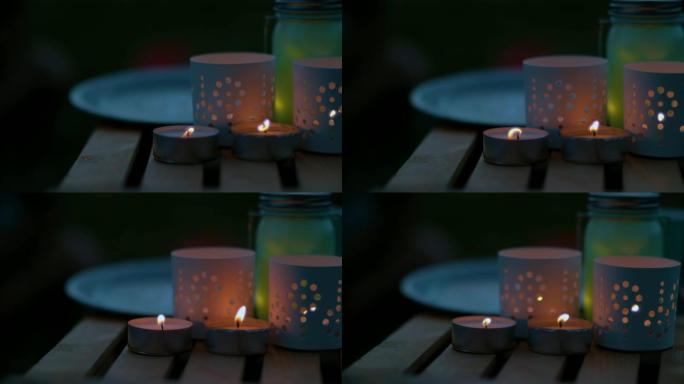 宏观: 夏日傍晚，小蜡烛在木制花园桌子上闪烁。
