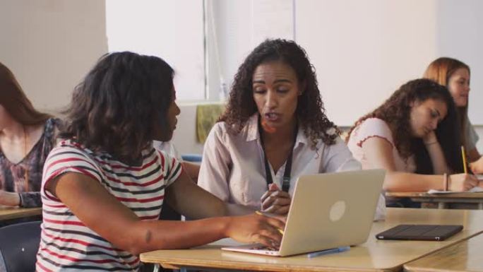 女教师为在笔记本电脑上工作的女学生提供一对一的支持