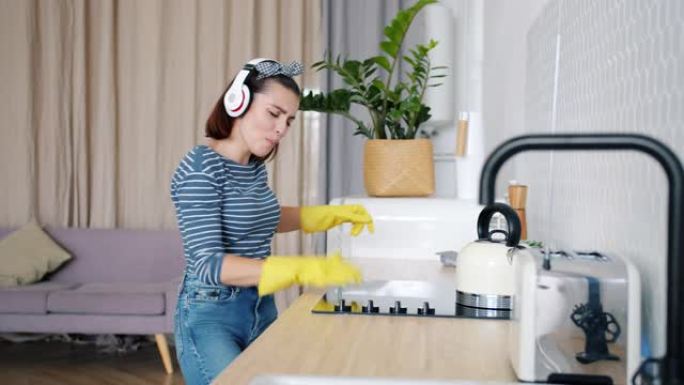 快乐的女士打扫厨房，然后跳舞唱歌，戴着耳机享受音乐