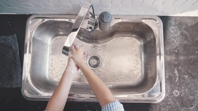 女人用水和肥皂洗手的俯视图