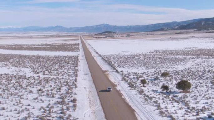 空中: 风景秀丽的沥青带领银色SUV穿越白雪皑皑的风景。