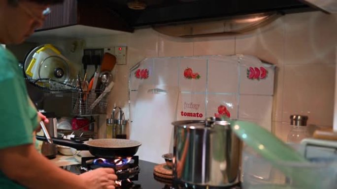 一名亚洲华人妇女在马来西亚执行限制行动令期间做煎饼准备做早餐