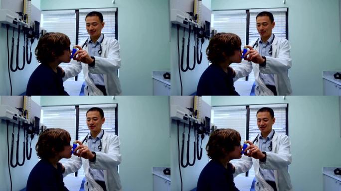 年轻的亚洲男性医生在诊所4k帮助一名白人男孩患者使用哮喘吸入器