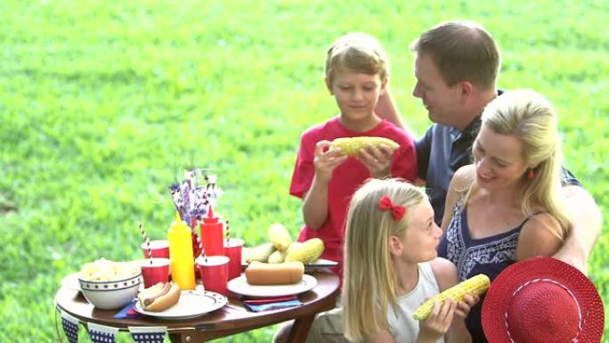 有两个孩子的家庭在7月4日野餐，吃玉米