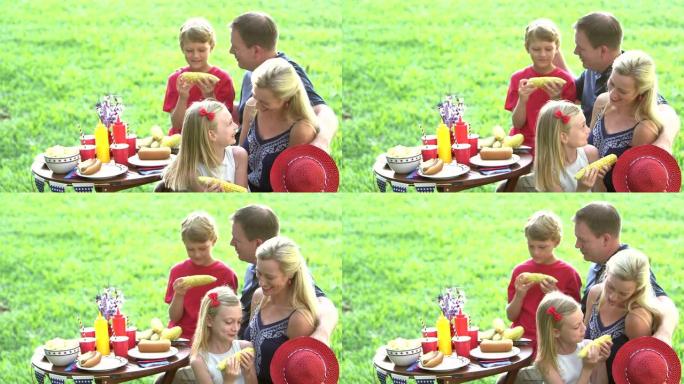 有两个孩子的家庭在7月4日野餐，吃玉米