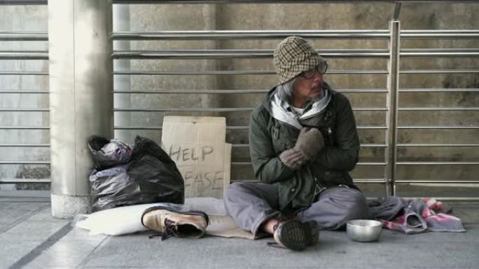 无家可归的老人坐在人行道上。