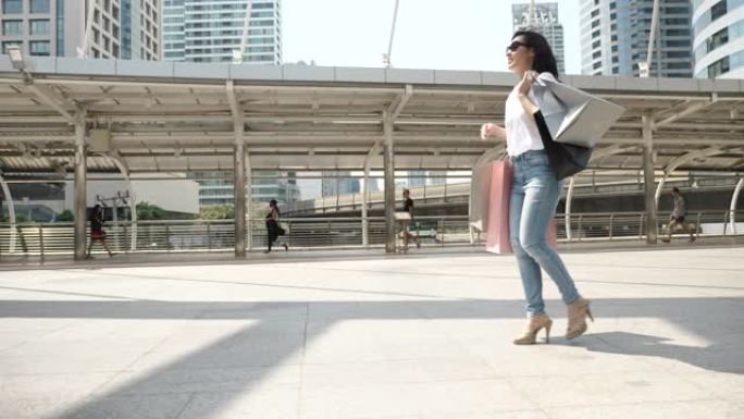 亚洲女人在城市里带着购物袋散步