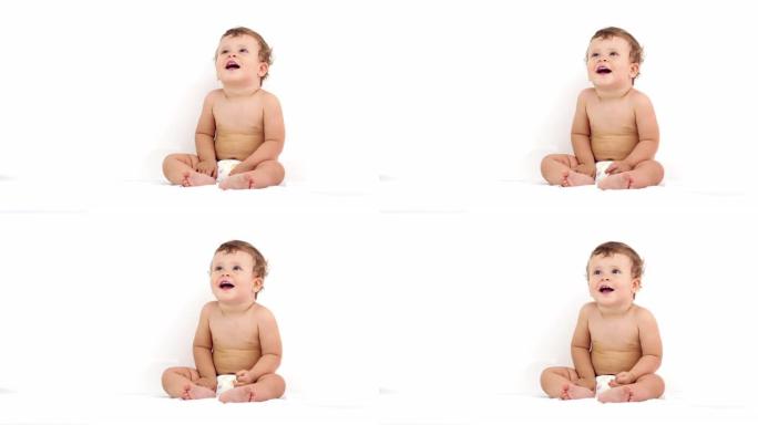 一个可爱的婴儿穿着尿布坐起来微笑的肖像。
