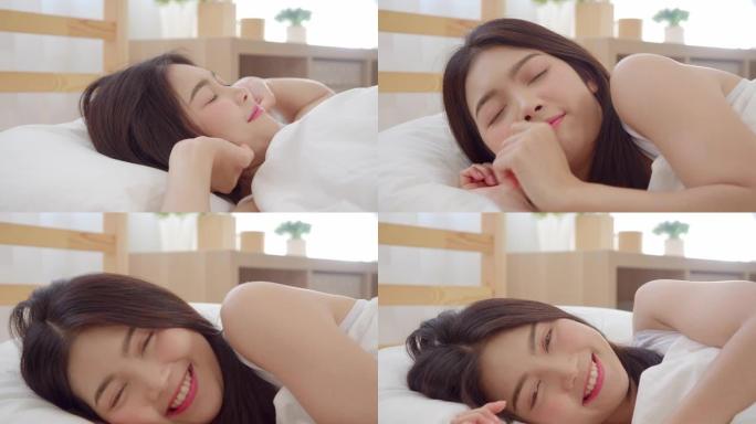 亚洲女人微笑着躺在卧室的床上，美丽的日本女人在家醒来后使用放松时间。生活方式女性使用在家放松时间的概