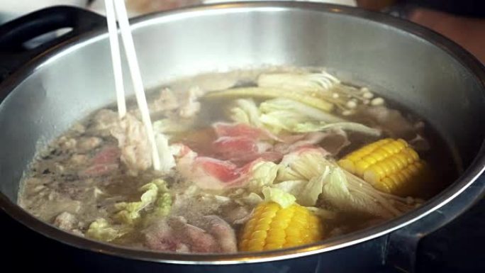 4k镜头煮汤火锅用筷子、沙锅、寿喜烧搅动和采摘薄片猪肉的场景日式美食概念