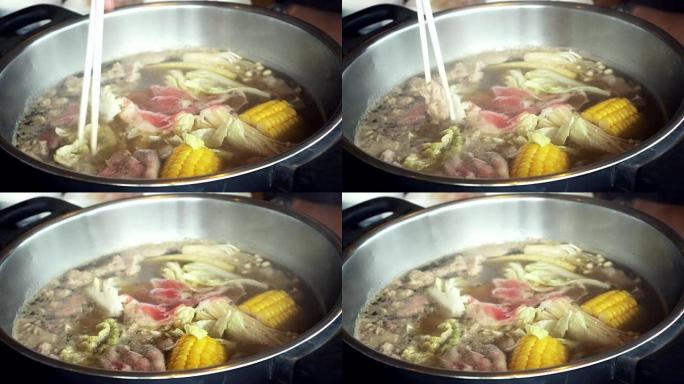 4k镜头煮汤火锅用筷子、沙锅、寿喜烧搅动和采摘薄片猪肉的场景日式美食概念