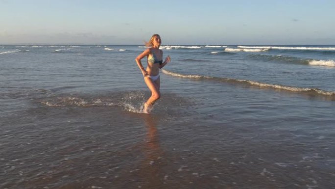 南非海滩浅水中奔跑的美丽年轻女子的4k慢动作视图