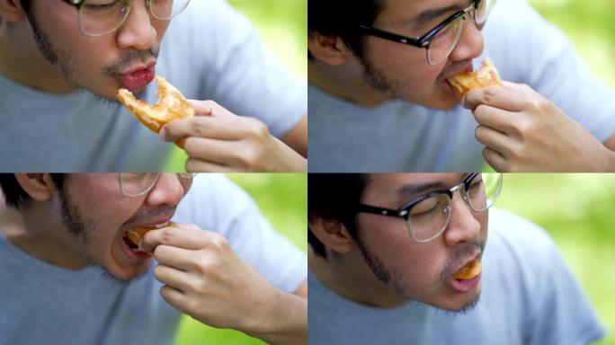 戴眼镜的亚洲男子吃奶酪切片的法式面包配莎莎酱