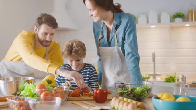 厨房: 三口之家一起烹饪健康晚餐。母亲和父亲教小男孩健康的习惯，并切蔬菜作为晚餐沙拉。可爱的孩子帮助