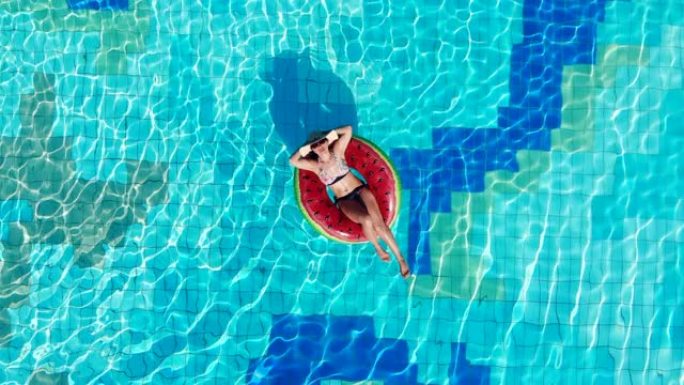 女人坐在游泳池里，漂浮在橡胶圈上。