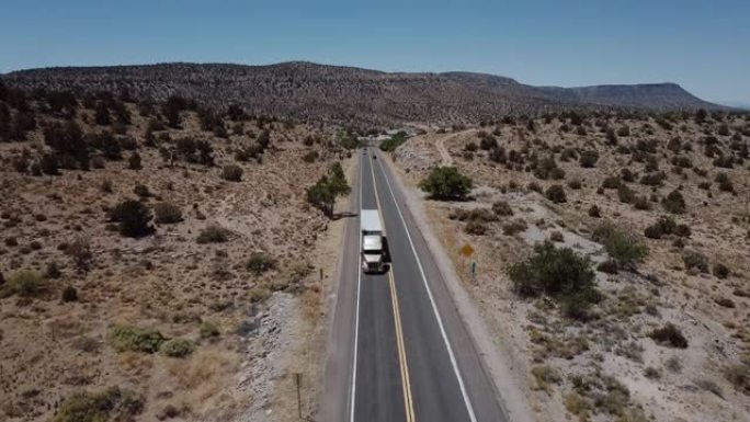 在美国亚利桑那州炎热的夏天，无人机在沿着美丽的砂岩沙漠山路行驶的大型送货卡车上倾斜。
