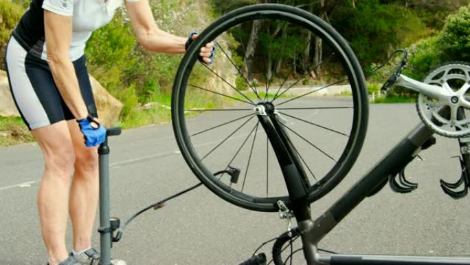 中年运动员在4k乡村公路用自行车泵泵送自行车轮胎