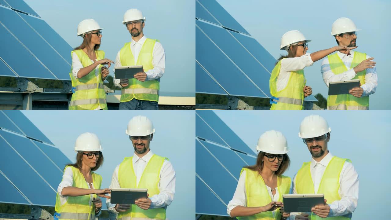 可再生能源概念。两名energetics员工正在用平板电脑沿着太阳能建筑行走