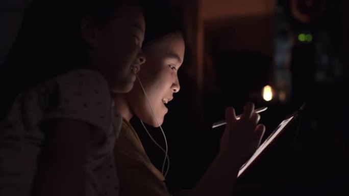 可爱的美丽的亚洲女孩用数码笔在平板电脑上在家和姐姐一起学习
