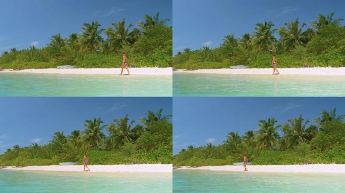 慢动作: 年轻女子在马尔代夫田园诗般的白色沙滩上漫步。