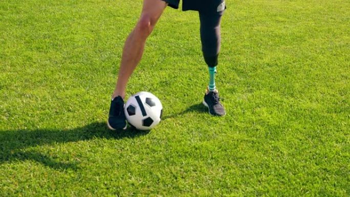 一个有仿生腿的男人在绿色草坪上运球