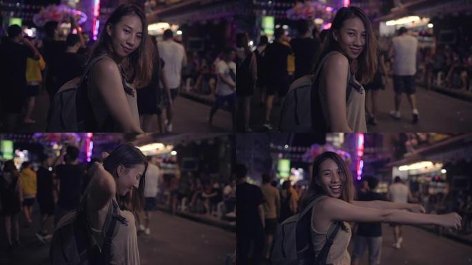 慢动作-年轻的亚洲旅行女性背包客在泰国曼谷考山路的城市街头夜晚派对上喝酒或啤酒跳舞。旅行者和旅游概念
