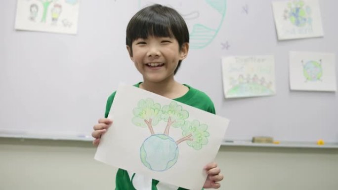 穿着绿色生态t恤的小男孩肖像，拿着他关于拯救世界项目的图纸。志愿者、自然和教育理念。