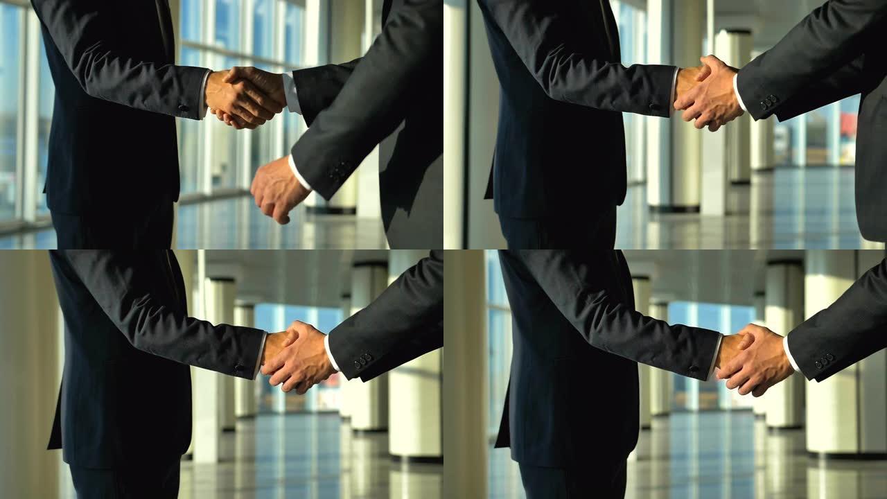 两个商人在办公大厅握手。慢动作
