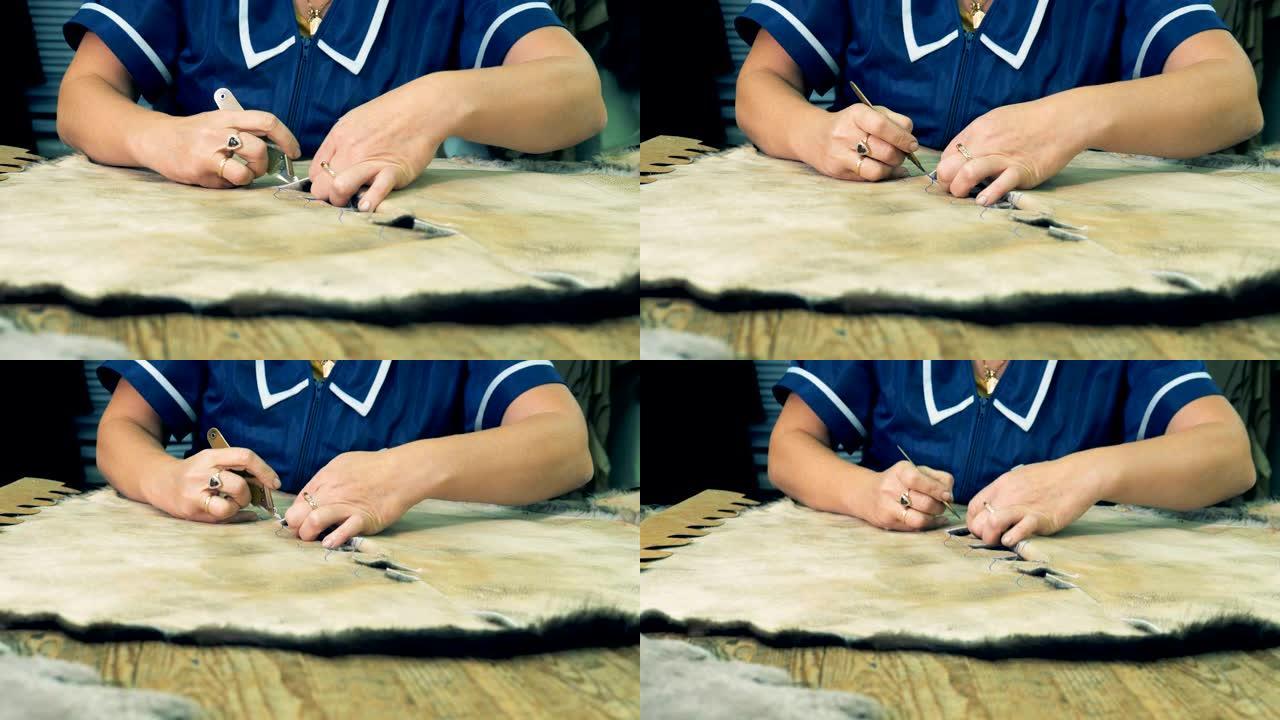女人用刀在桌子上切动物皮，特写。