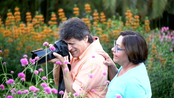 高级西班牙裔夫妇在公园拍摄鲜花