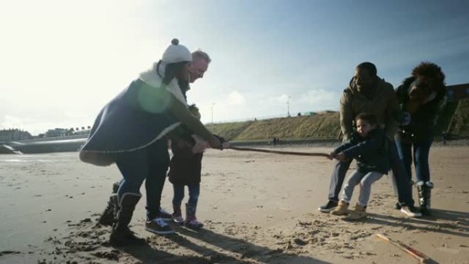 三代家庭在沙滩上玩拔河比赛