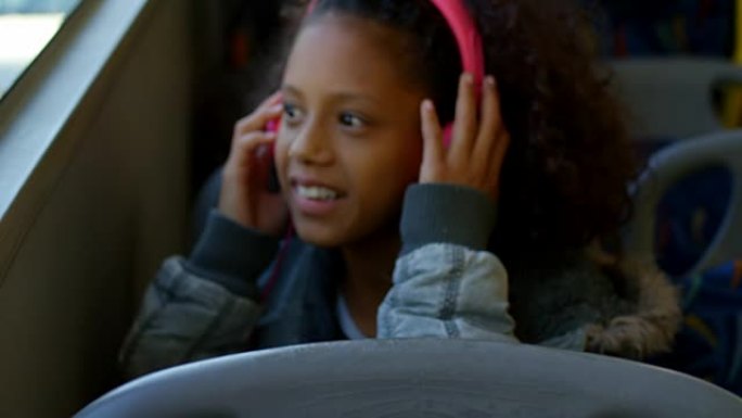 女孩在4k公共汽车上旅行时戴着耳机听音乐