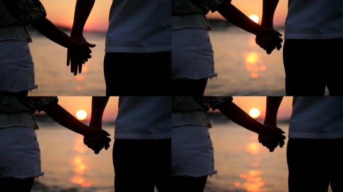 夫妇在海滩上牵手牵手夕阳西下背影