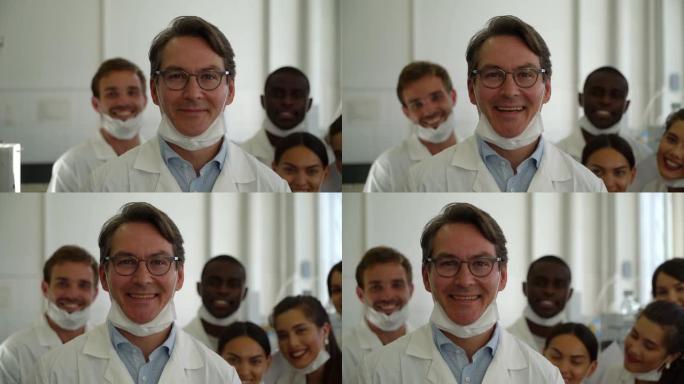 实验室里开朗的老师面带微笑，一群学生站在他身后