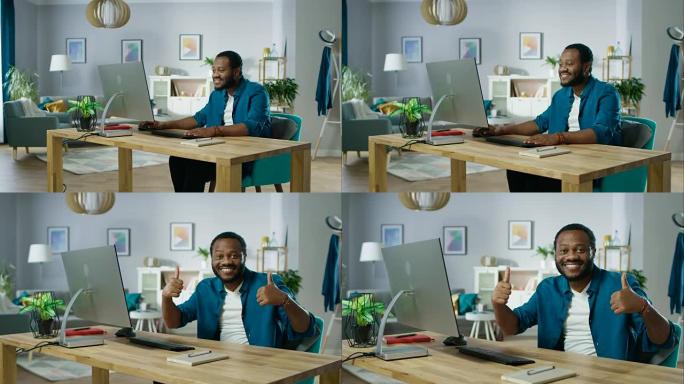 放大这位英俊的黑人在个人电脑上工作的肖像，取得了成功，并用双手竖起大拇指。背景舒适的客厅。